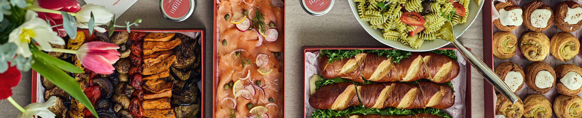 שולחן ערוך עם ירקות בגריל, סלמון מעושן עם צנוניות, פסטה פסטו עם עגבניות, לחמניות פרצל רכות, מאפים ואגרטל פרחים. - Cassarole