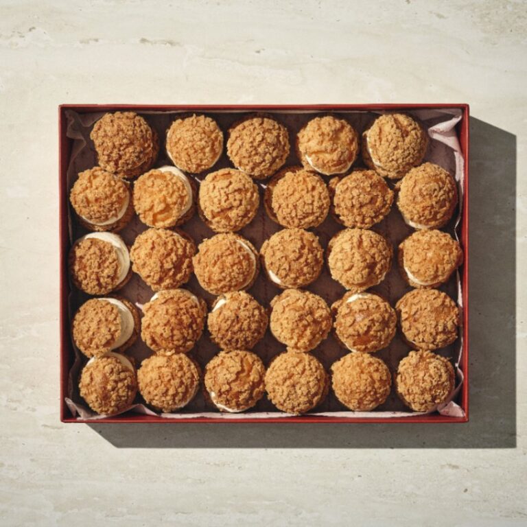 קופסה של 25 "הפחזניות של קסרולה" מאפים ממולאים בקרם, מסודרים ברשת 5x5 על משטח בהיר. - Cassarole