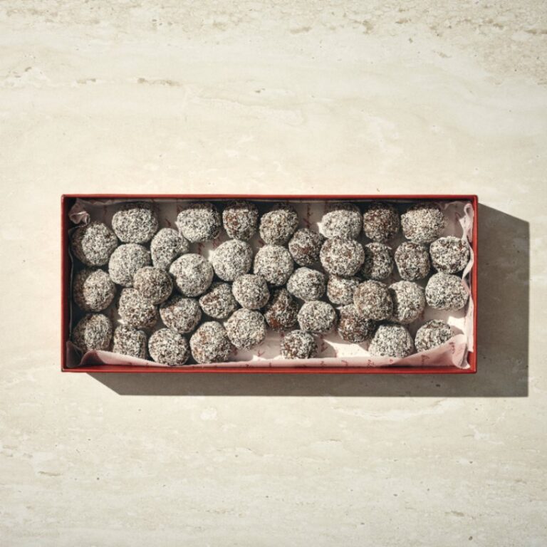 קופסה מלבנית מלאה בכדורי שוקולד מסודרים בקפידה, כל טראפל שוקולד מצופה אבקת סוכר. - Cassarole