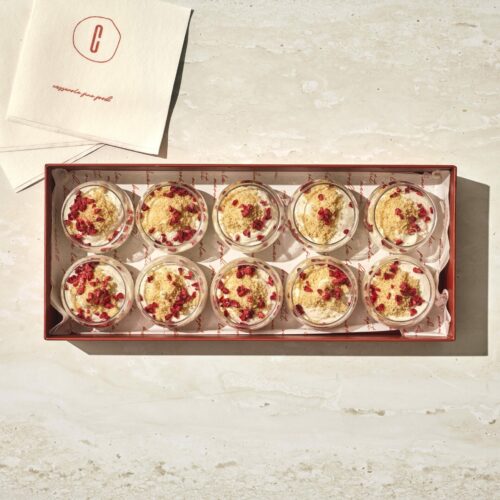 קופסה של עשרה גביעי מוס מסקרפונה עם פירורים מעל מונחת על משטח בהיר לצד מפיות ממותגות. - Cassarole