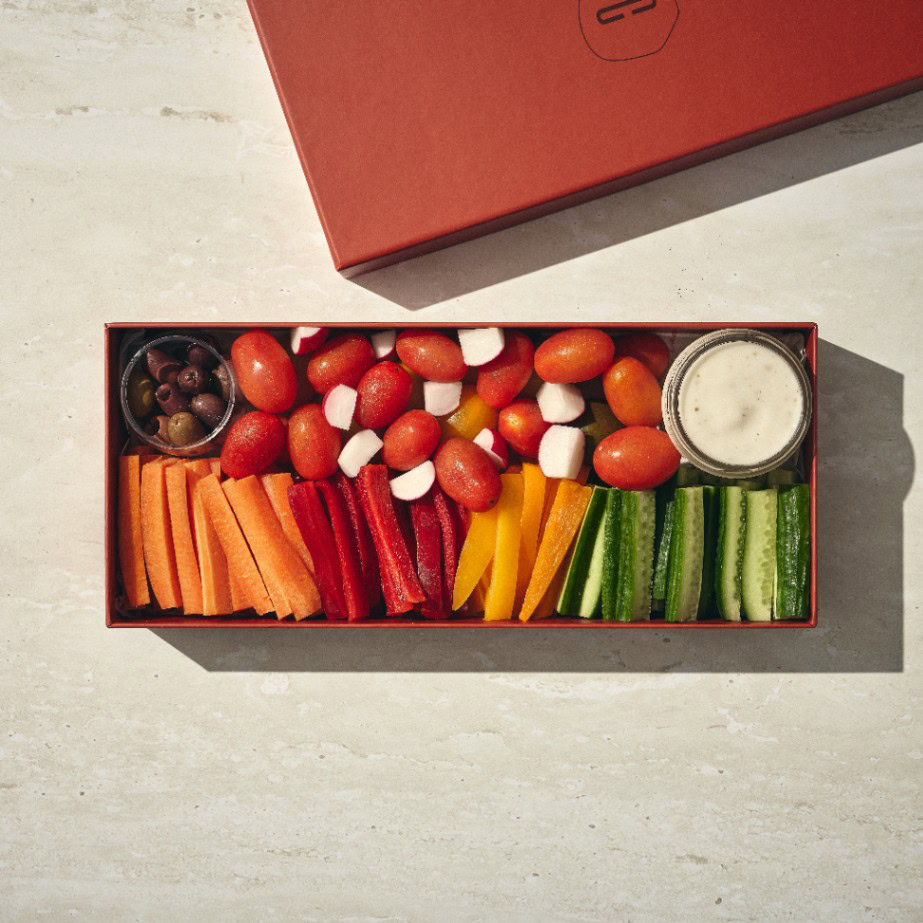 קופסה מלבנית של נשנושי בריאות (קטן) עם עגבניות שרי, חתיכות מוצרלה, גזר, פלפל אדום וצהוב, מקלות מלפפון, זיתים שחורים וכוס רוטב ראנץ'. - Cassarole