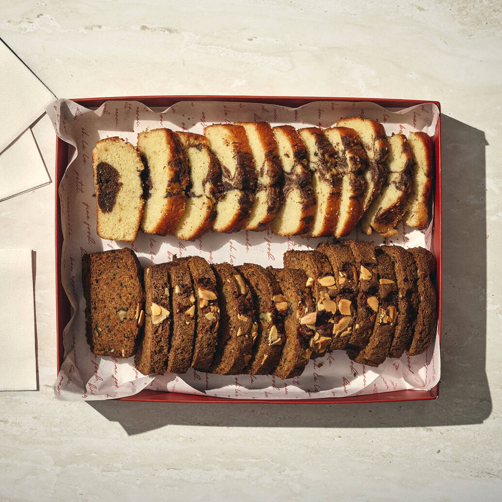 קופסה עם שתי שורות של עוגות פרוסות: אחת בהירה עם מערבולת כהה, והשנייה כהה עם אגוזים מעל. שתי מפיות מקופלות מונחות לצד הקופסה. - Cassarole