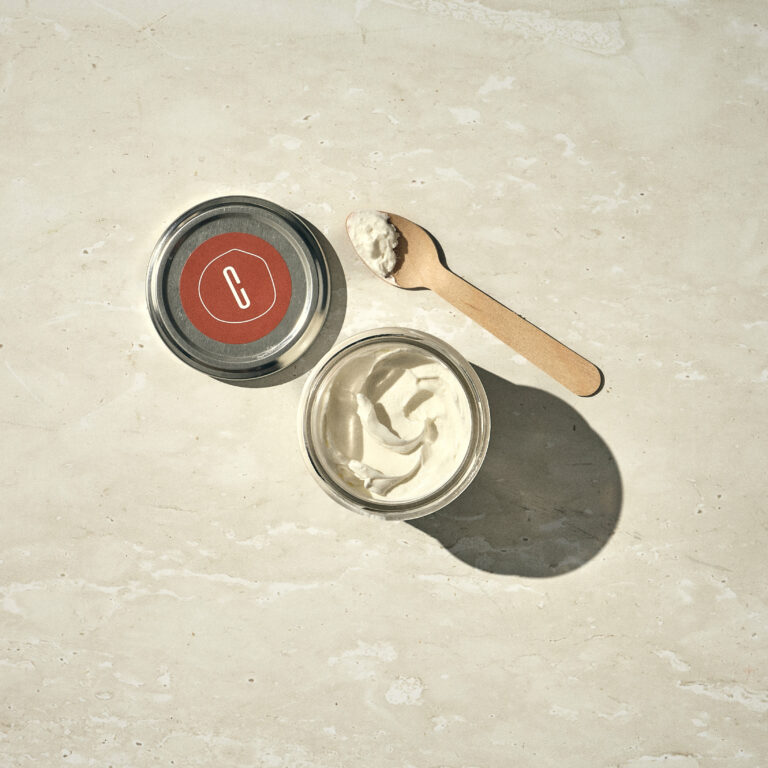 צנצנת זכוכית של שמנת עם מכסה מתכת וכף עץ על משטח אבן בהיר. - Cassarole